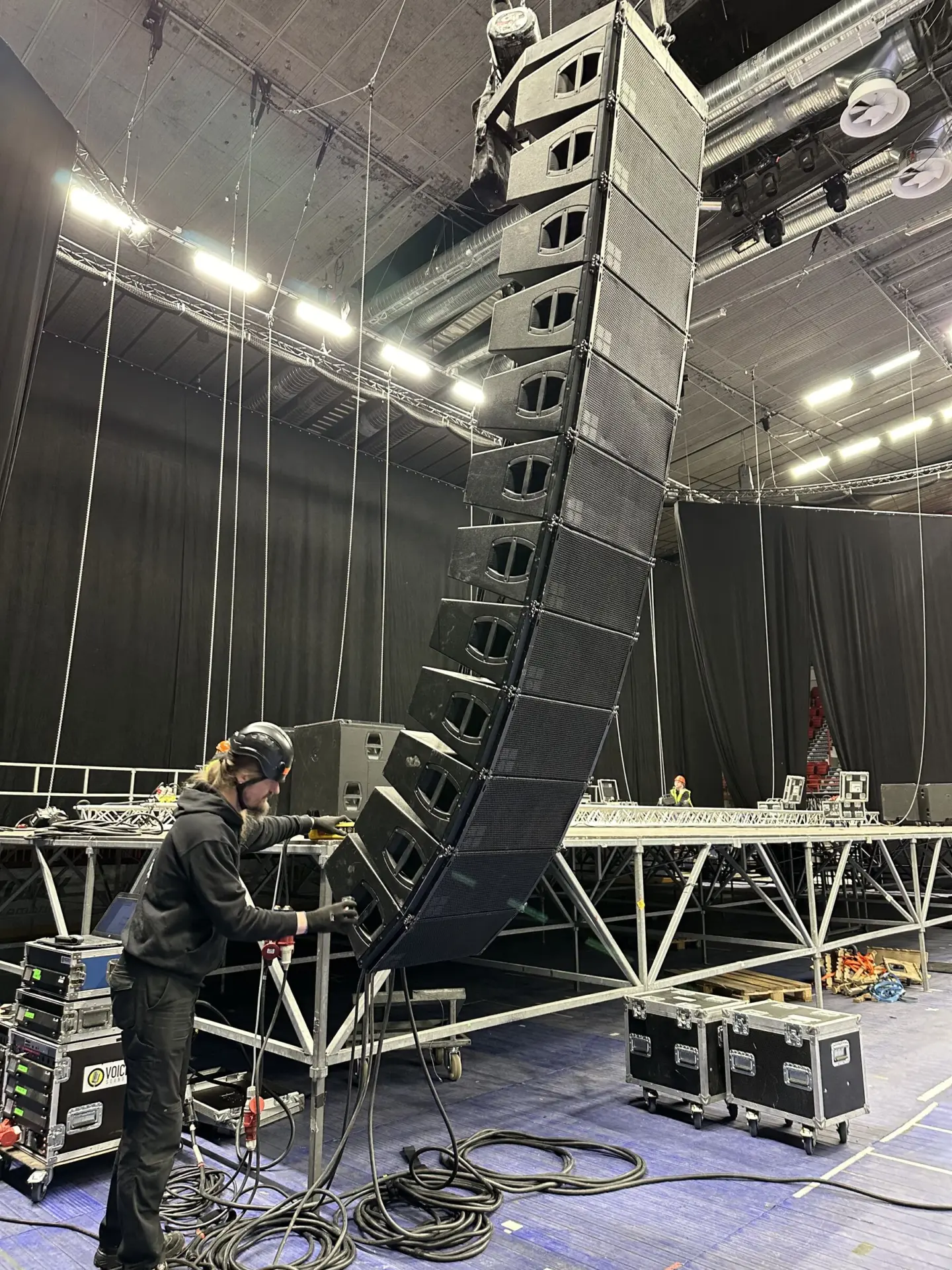 Teknikko rakentaa line array -kaiutinjärjestelmää lavalla