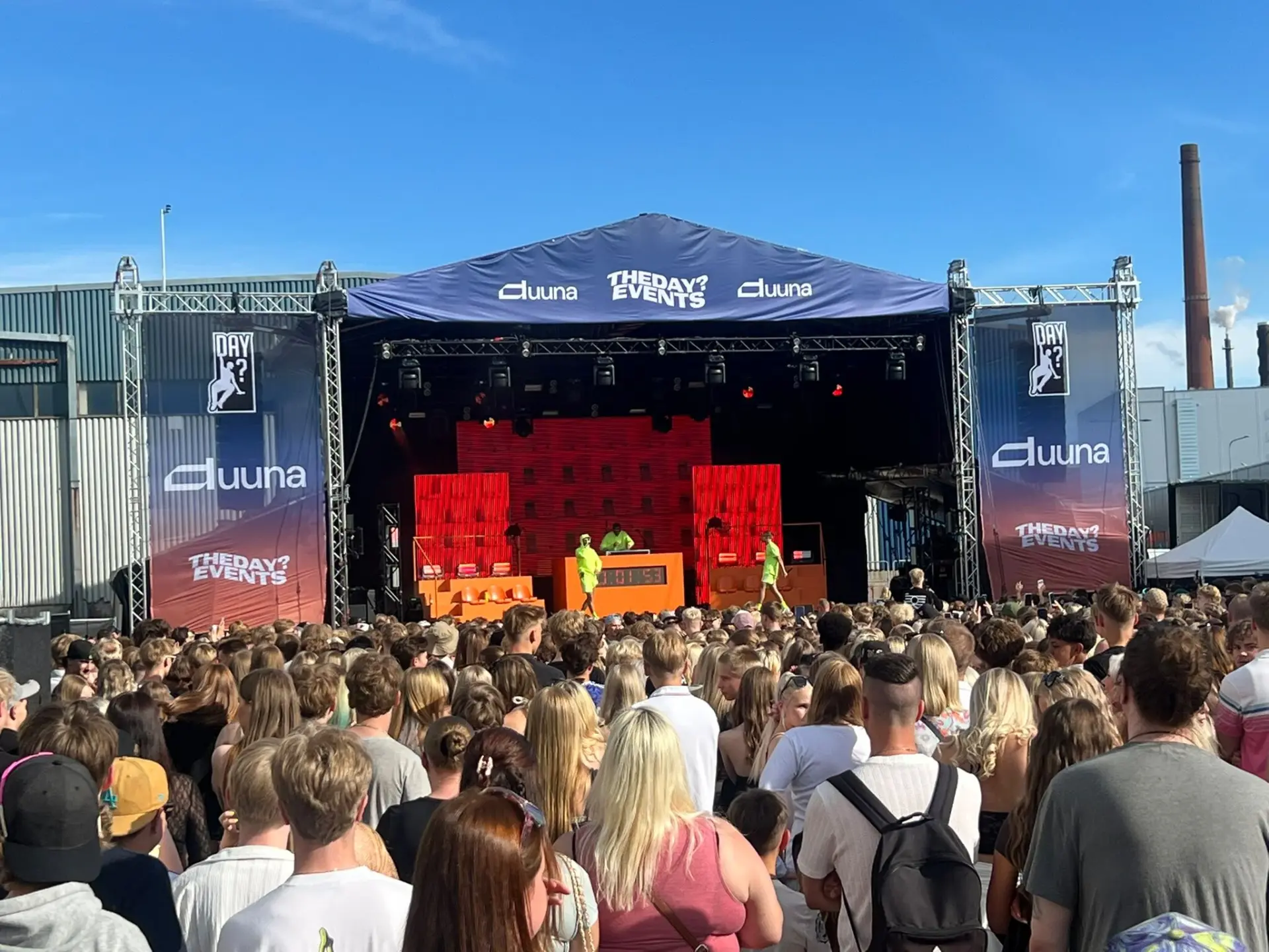 Ulkolava, mainosbanderollit ja festivaaliyleisö aurinkoisena päivänä