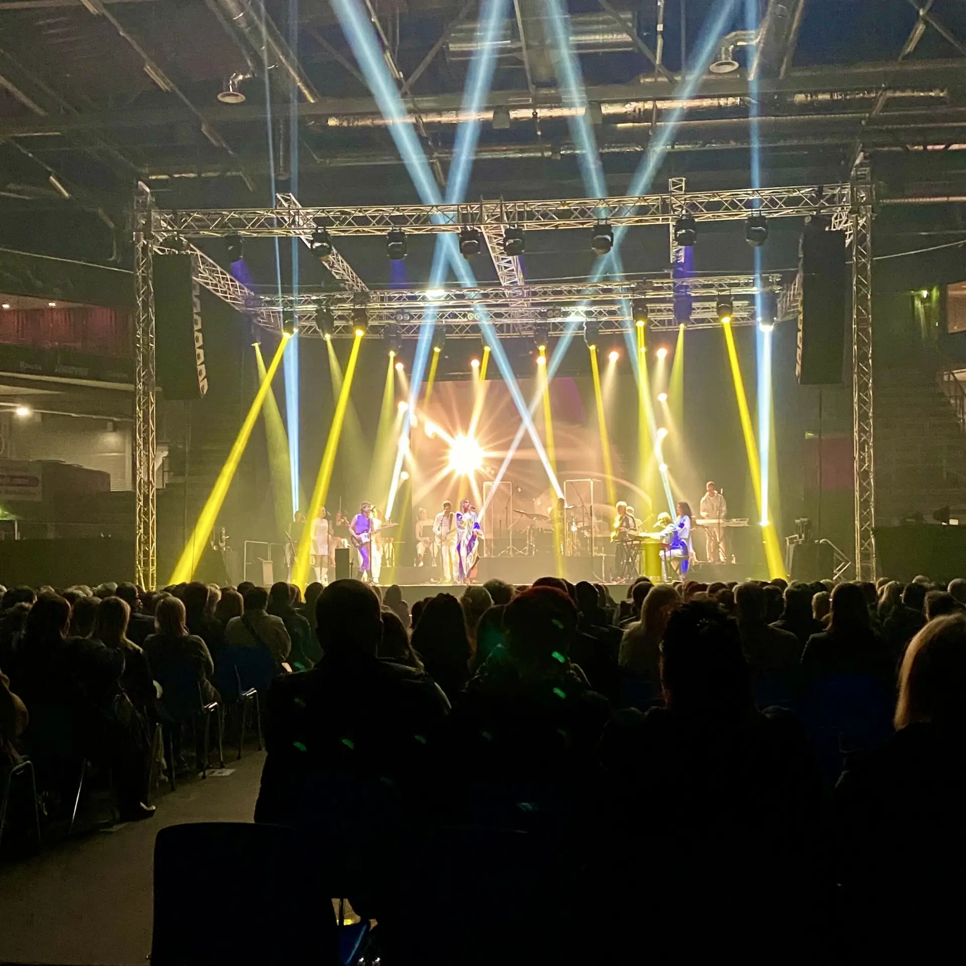 Konsertin valoshow, keltaiset ja valkoiset valonsäteet lavalla